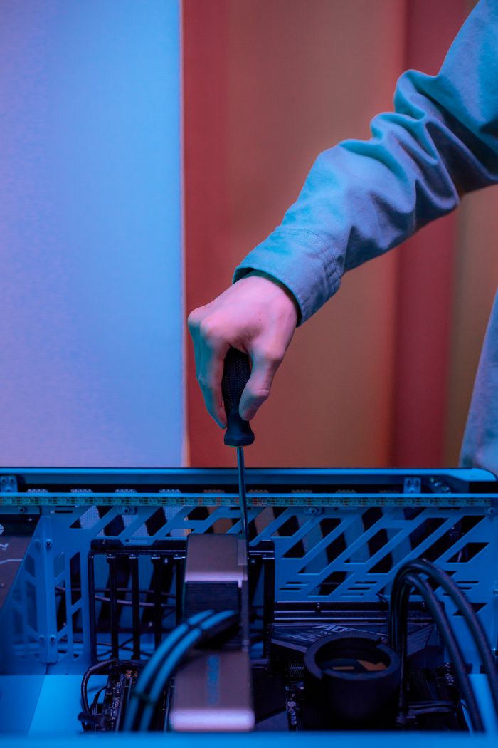 Close-up of hand using screwdriver inside PC tower, illustrating technology repair.